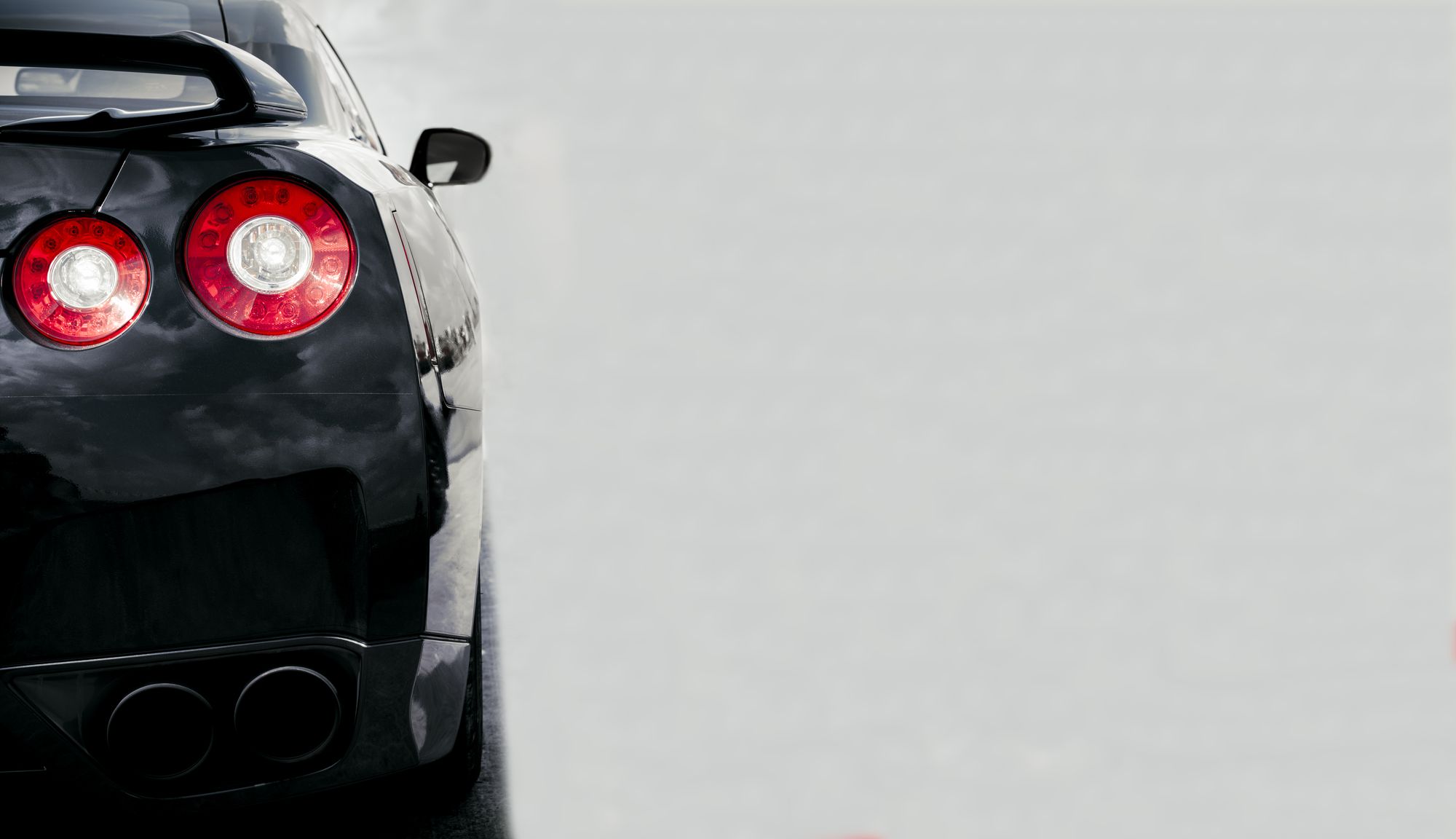The rear of a black Nissan GT-R on an open road